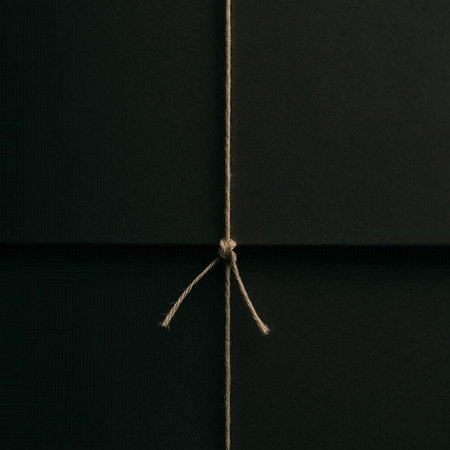 Black envelope with string on a dark background. Close-up.