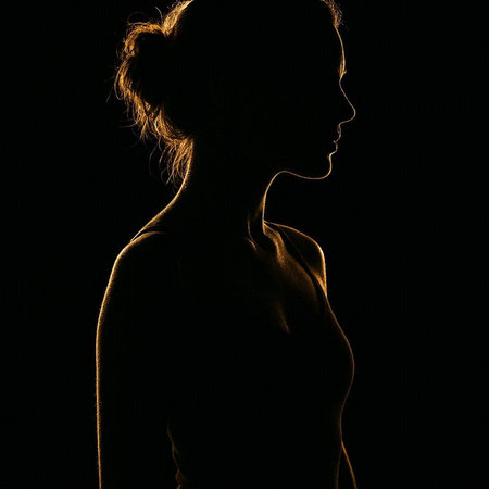 Silhouette of a beautiful young woman on a black background.の写真素材
