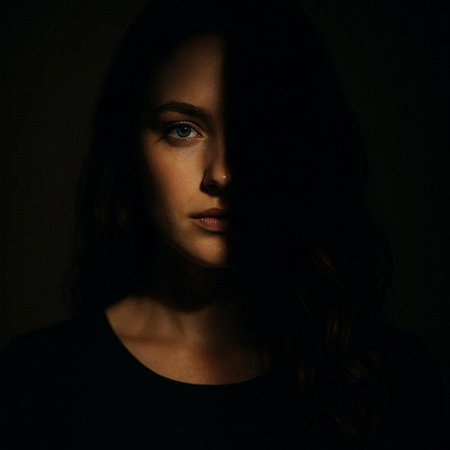 Portrait of beautiful young woman with long wavy hair on dark backgroundの写真素材
