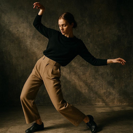 Modern style dancer posing in studio. Wearing brown pants and black sweater.