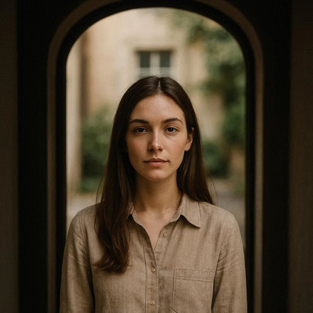 Portrait of a beautiful young woman with long brown hair, wearing a beige shirt.