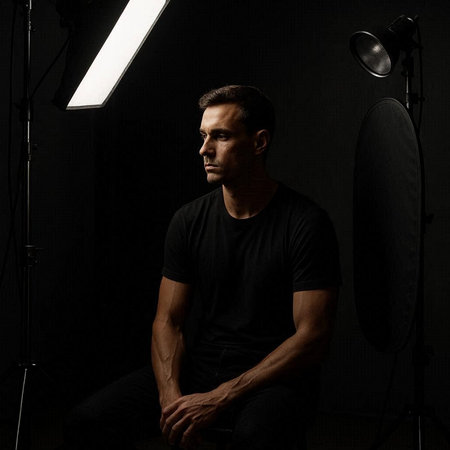 Portrait of a handsome man in a black T-shirt sitting on a chair in a photo studio