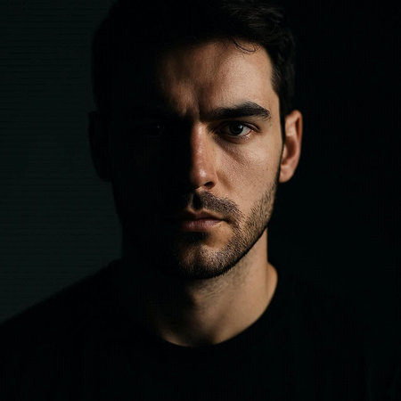 Portrait of a handsome young man in black t-shirt on dark background