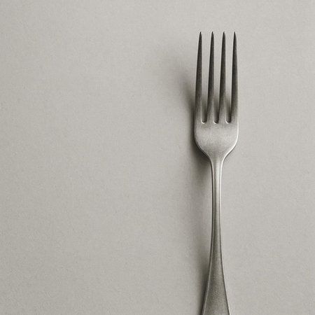 Silver fork on a gray background with copy space, top view.