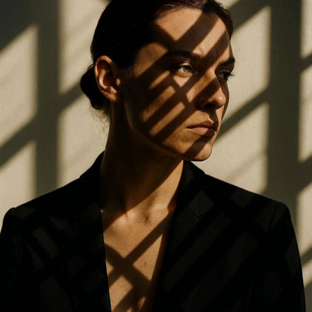 Portrait of a young beautiful woman in a black coat with shadows on the wallの写真素材