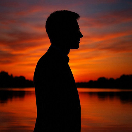 Silhouette of a man at sunset on the river bank.の写真素材