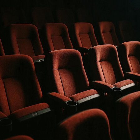 Interior of an empty cinema auditorium with rows of red seatsの写真素材