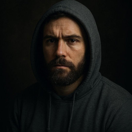 Portrait of a brutal man with a beard and mustache in a black sweatshirt on a dark backgroundの写真素材