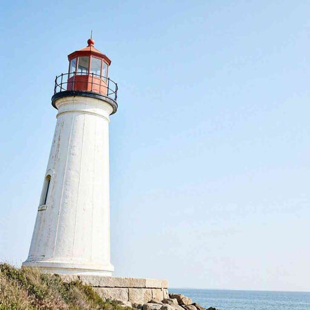 Lighthouse on the seashore with blue sky in the background