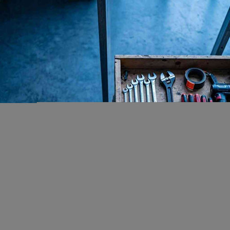 A set of tools in a wooden box on the background of a gray wall