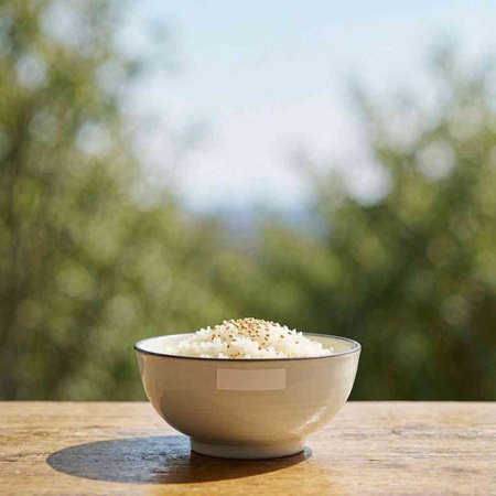 Rice in a bowl on a wooden table with blurred background.