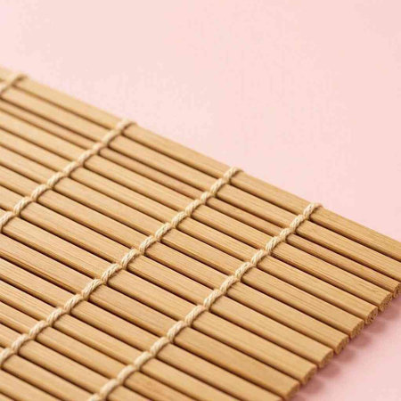 Bamboo mat on pink background with copy space for your text.