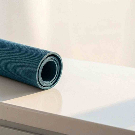 Blue yoga mat on a white table with copy space for text.