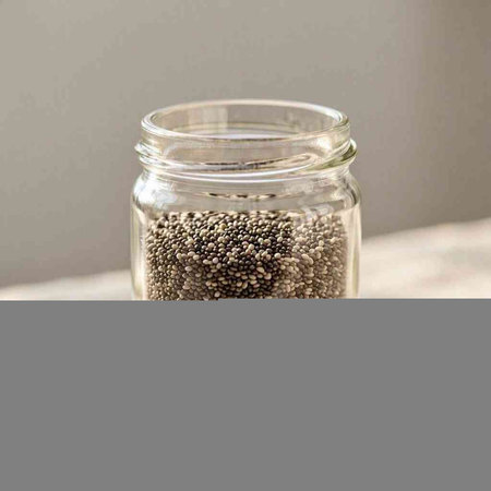 Chia seeds in a glass jar on a gray background. Selective focus.