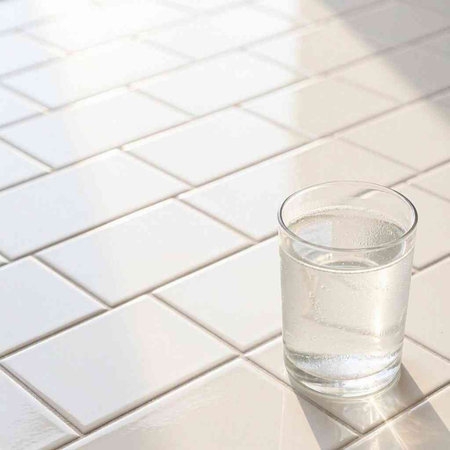 Glass of water on a white tile floor. Close-up.