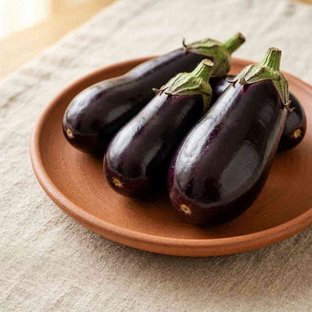 Eggplants in a clay plate on a linen tablecloth