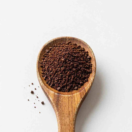 Coffee powder in a wooden spoon on a white background.