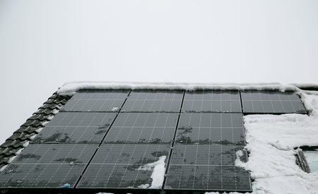 Solar panels on the roof of a house covered with snow in winter