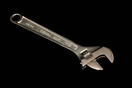 An adjustable wrench, tools isolated on black.