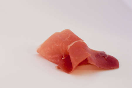 A thin slice of Prosciutto Di Parma on a white background.の写真素材