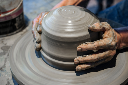 Potter at work on pottery wheel (close up hands and gray clay)の写真素材