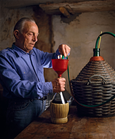 An old man puor the wine into the flask, in his cellarの写真素材