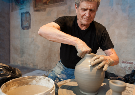 Certaldo, Tuscany, Italy - July 13, 2017: Old artisan maestro making clay pot terracotta on the pottery wheel, atの写真素材