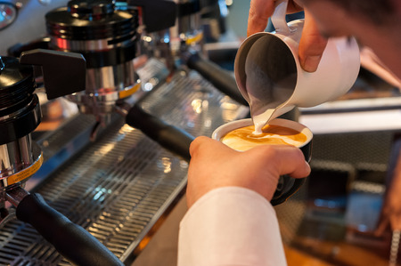 Puoring milk in a coffee cup, preparing italian cappuccino, with professional espresso machineの写真素材