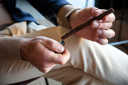 The smoker heats a Tuscan cigar with a lighter, before turning it on.の写真素材