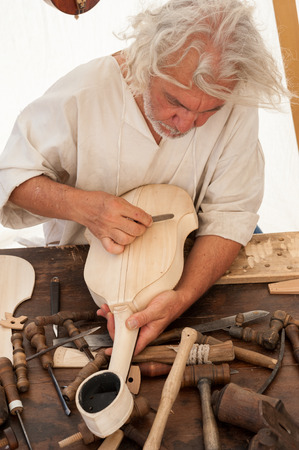 Luthier working on the creation of a stringed instrument. Various tools and instrument are placed on the workbenchの写真素材