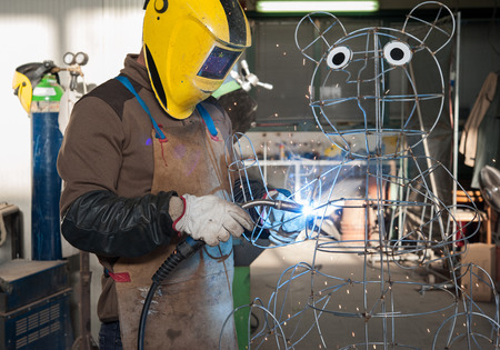 The welder builds the structure for a topiary plant sculpture