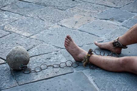 Prisioner with ball and chain in the court of the prison. Close up. Concept of inhuman and degrading detention conditions.のeditorial素材