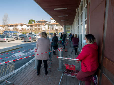 Florence, Italy - 2020, April 4: European consumers in line at the supermarket for grocery shopping,...