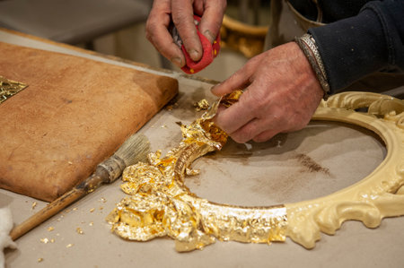 Application of gold leaf to a frame. Gilding process technique. Craftsman at work..の写真素材