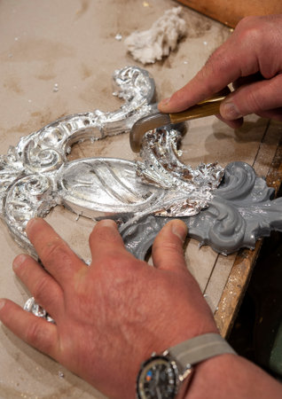 Silvered frame ready for burnishing with an agate stone tool. Silvering process technique. Craftsman at work..の写真素材