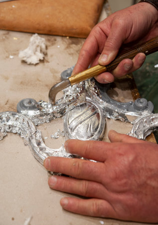 Silvered frame ready for burnishing with an agate stone tool. Silvering process technique. Craftsman at work..の写真素材