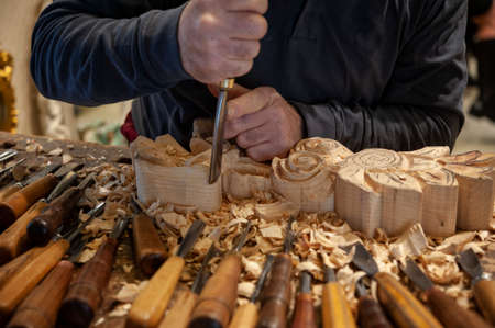 Master woodcarver at work. Wood shavings, gouges and chisels on the workbench. Close up.の写真素材