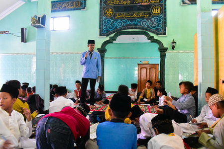 Kediri, Indonesia - June 12, 2023 : male student giving lesson explanation to children.のeditorial素材