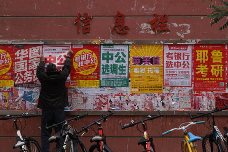 A man pastes a poster for an exam-preparing school at Zhengzhou University in Zhengzhou in central China's Henan province Wednesday Nov. 18, 2015. The National Graduate Schools Entrance Exam will be hold on 26 December.のeditorial素材