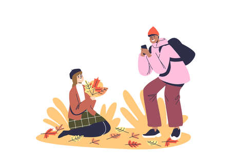Young couple enjoy taking photos in autumn leaves in park. Teen girl and boy spend time outdoors