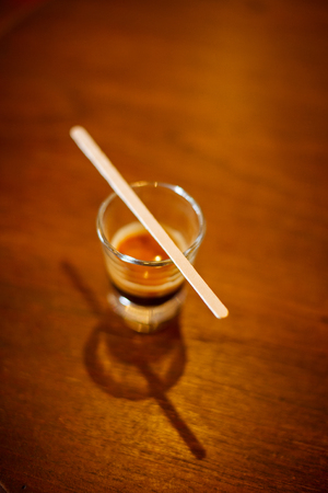 A cup of espresso shot coffee and stir stick on wooden table background with blank copy spaceの写真素材