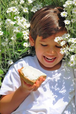 A little kid holding bread with white cream onの写真素材