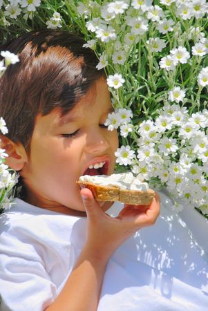 A little kid holding bread with white cream onの写真素材