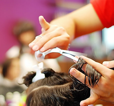 Hands holding scissors cutting hair