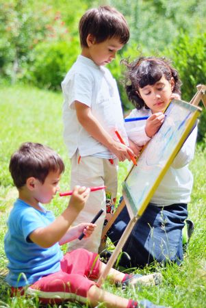 Happy three children playing outdoor and drawing on the boardの写真素材