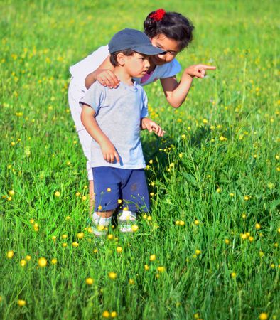 Girl and boy standing on green ground and looking asideの写真素材
