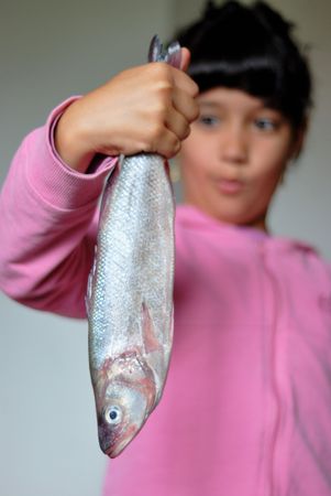 Girl holding big fish in hands with supprising expression on her faceの写真素材
