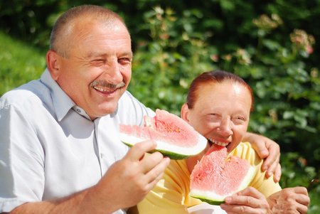 Happy elderly couple with water melon outdoorの写真素材