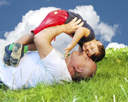 A grandfather and his kid laying and smiling on grassの写真素材