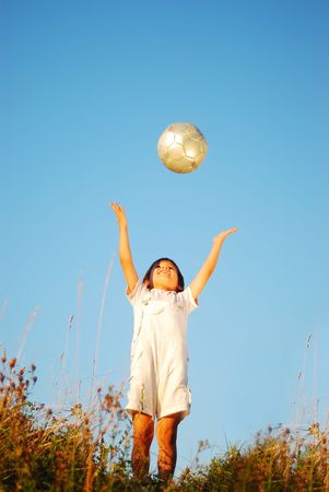 Little cute boy with ball above head in adorable place outdoorの写真素材